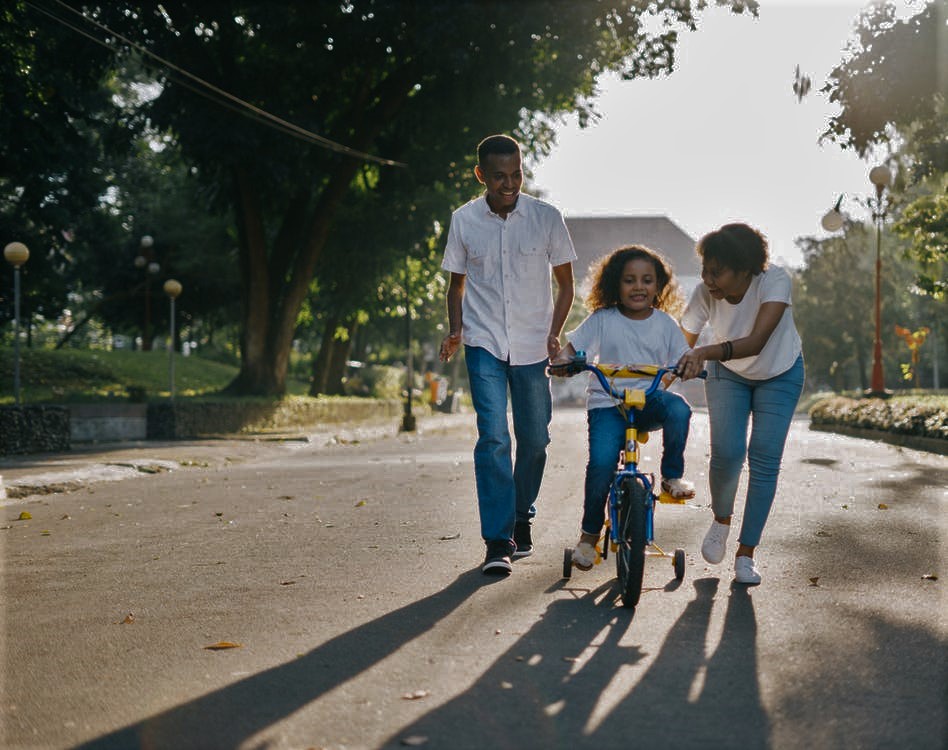 parents teaching kid to ride a bike